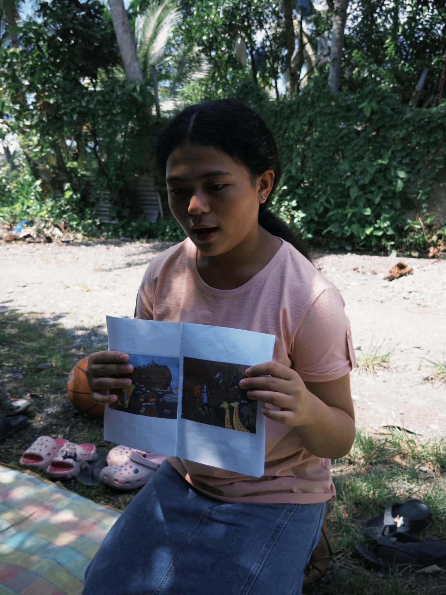 A young girl sharing printed pictures during an outdoor ministry activity