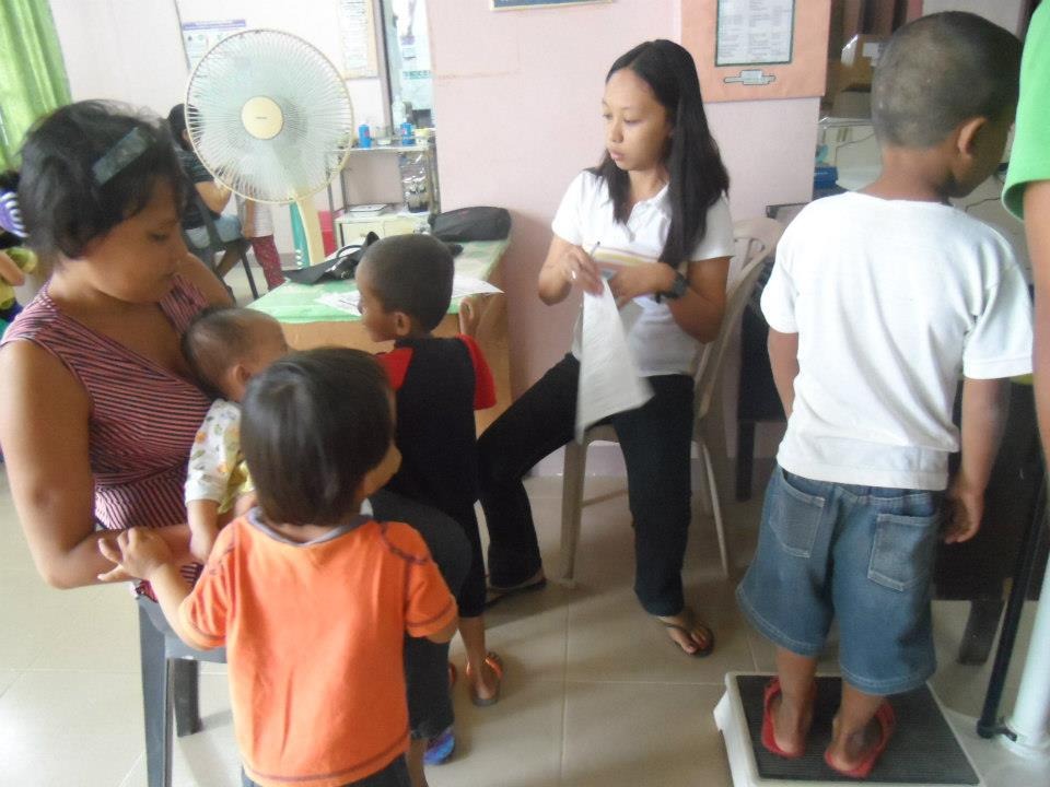 Community health worker registering mother and children during health checkup