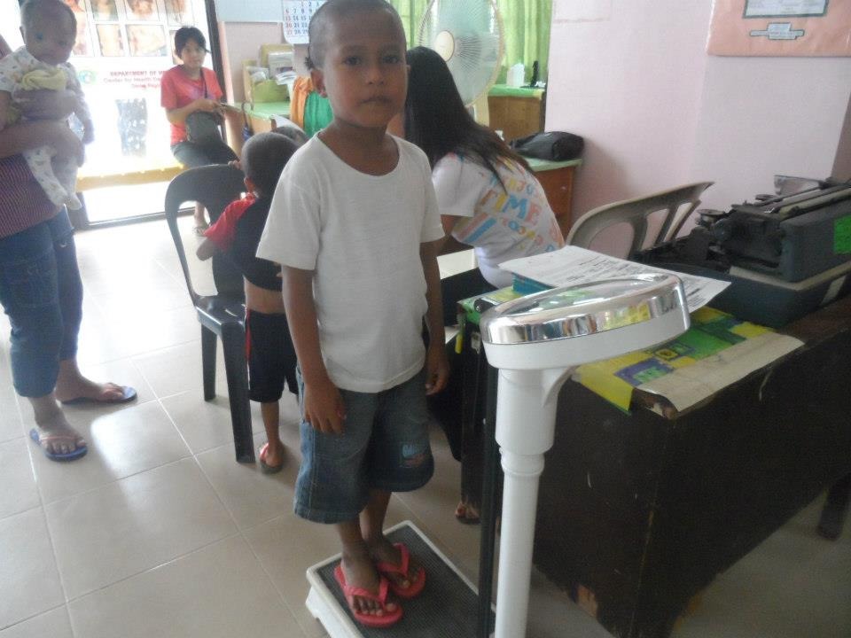 Young boy standing on weighing scale during health checkup