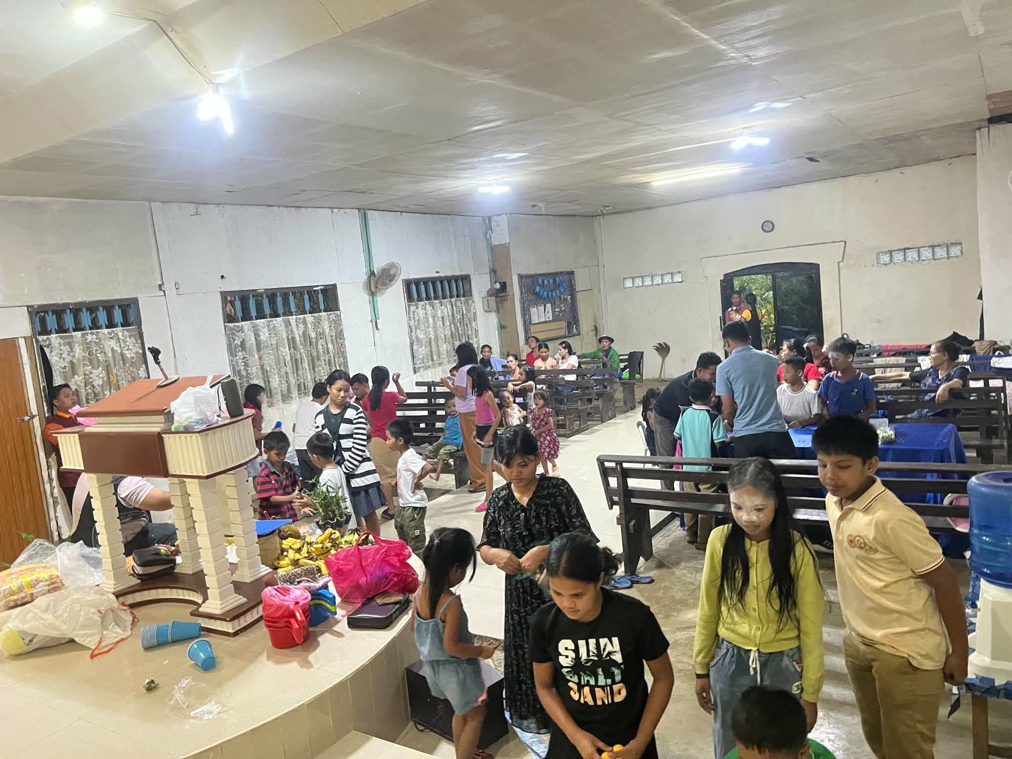 Families and visitors gathered among the pews in a church hall