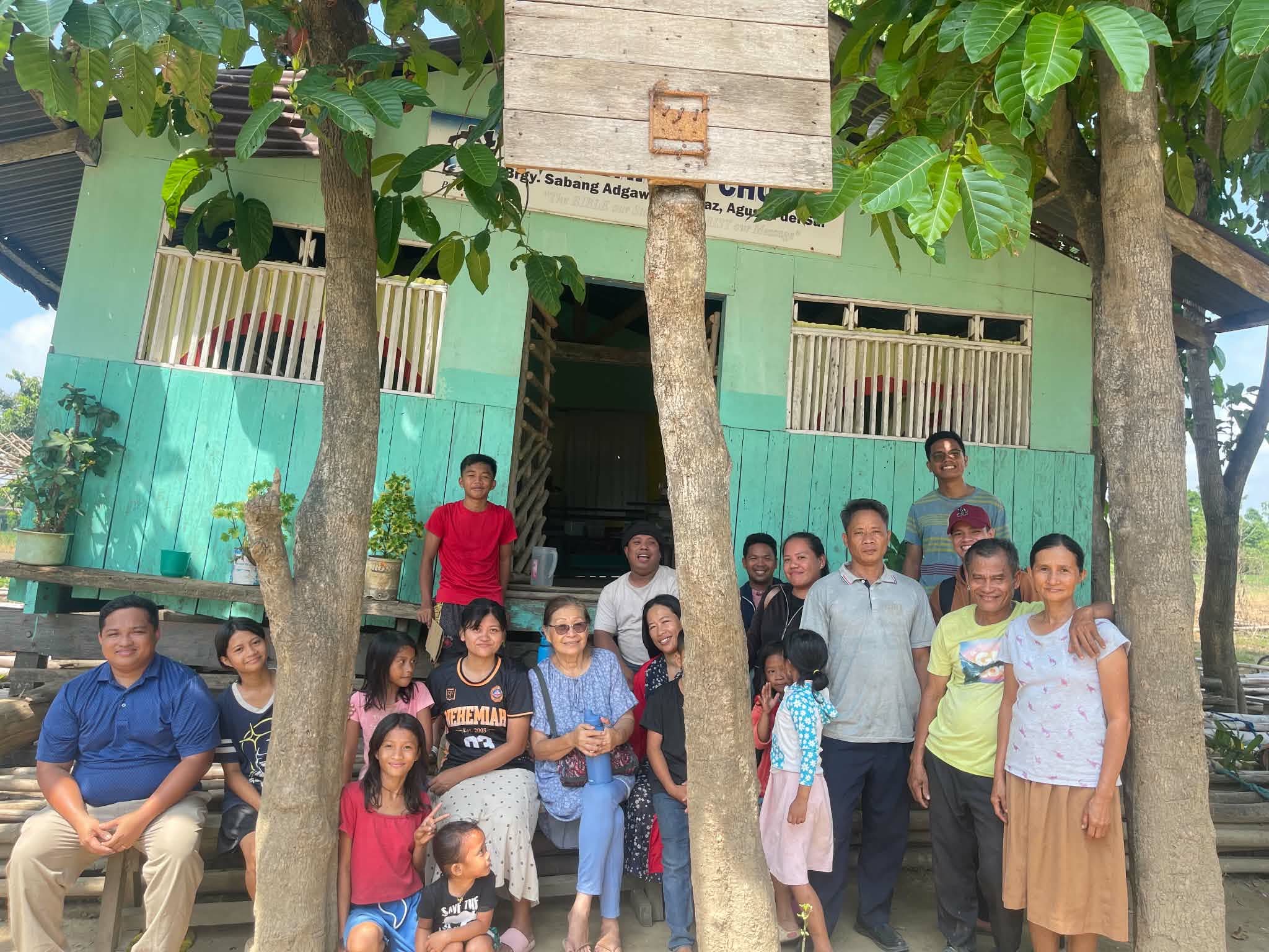 Adults and children gathered outside a green church building