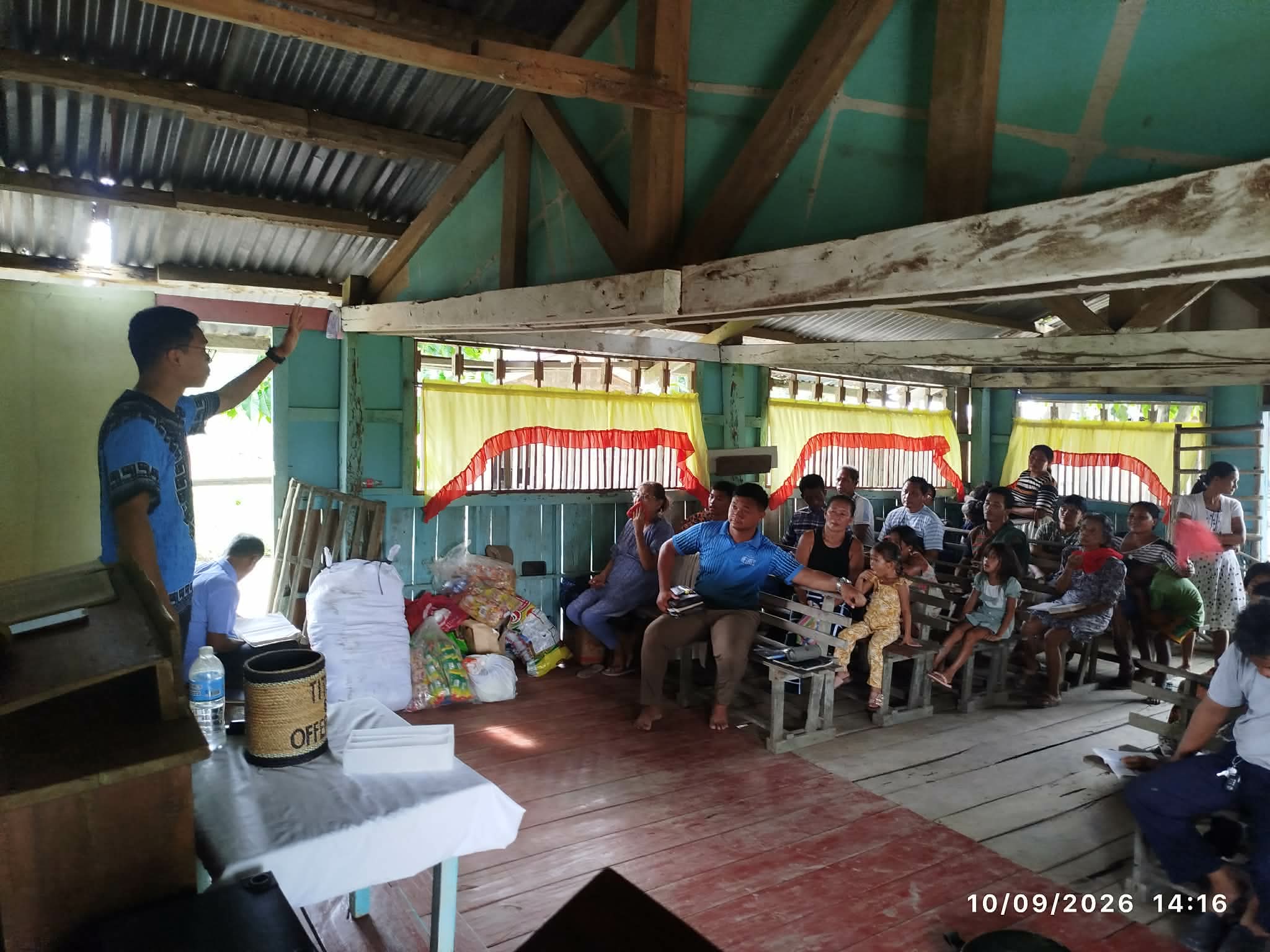 A speaker addressing people seated on wooden church benches