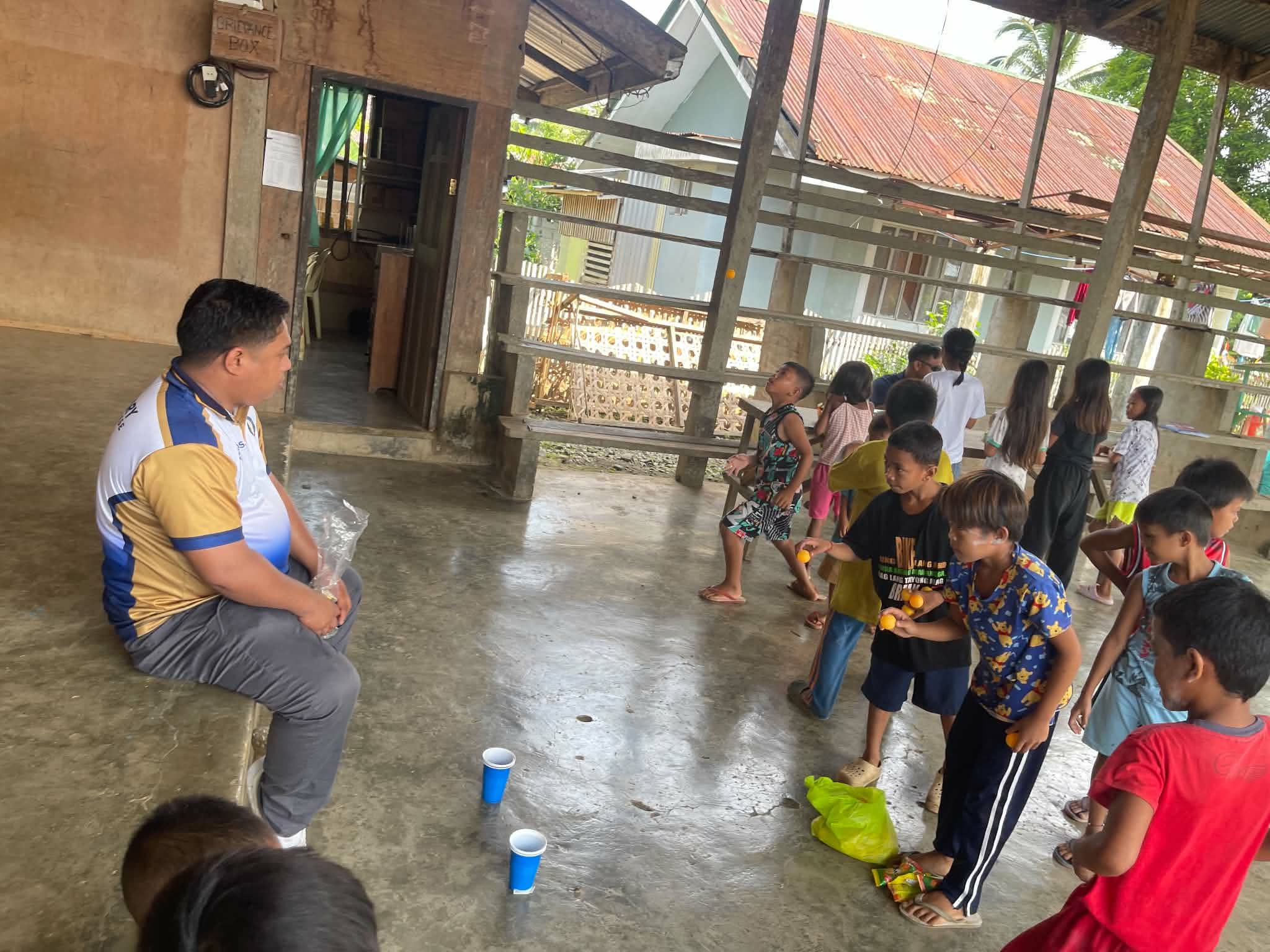An adult facing a row of children inside a covered gathering space