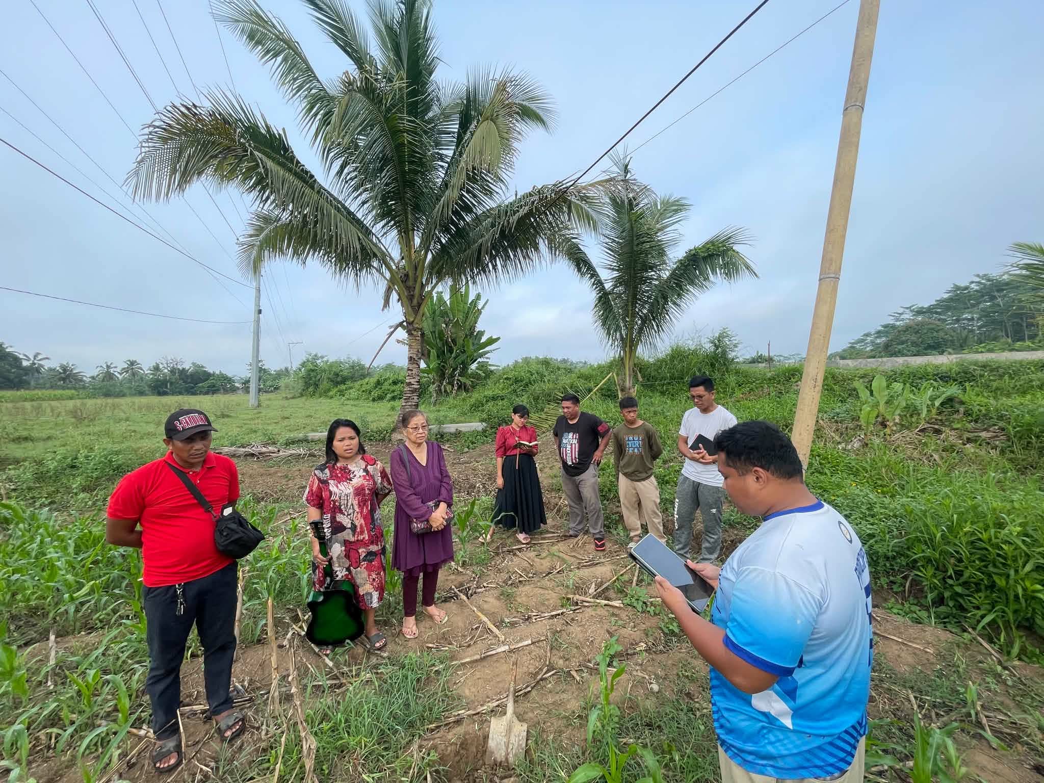 Mission visitors walking along a grassy path beside fields