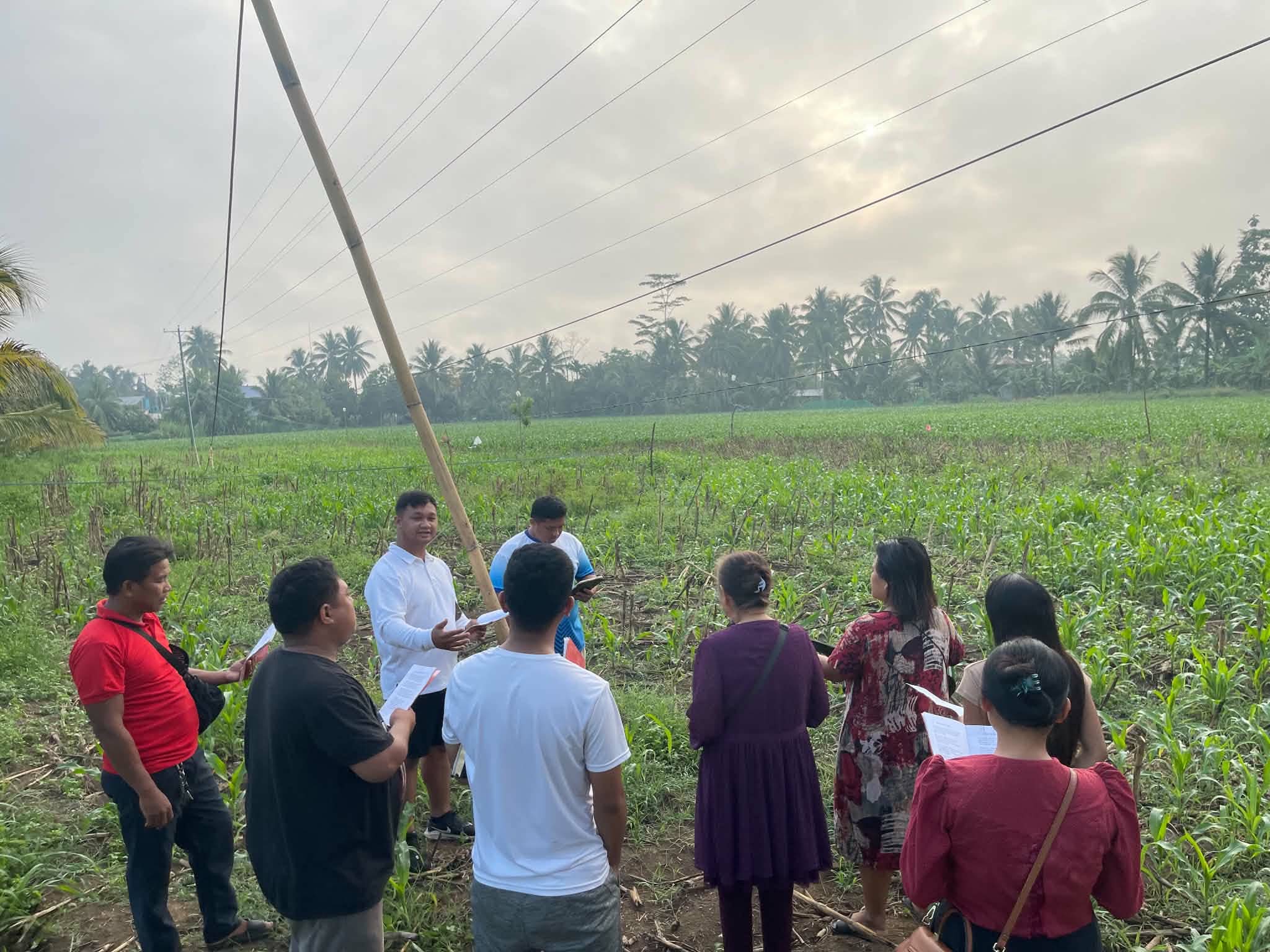A group gathered beside green fields along a rural path