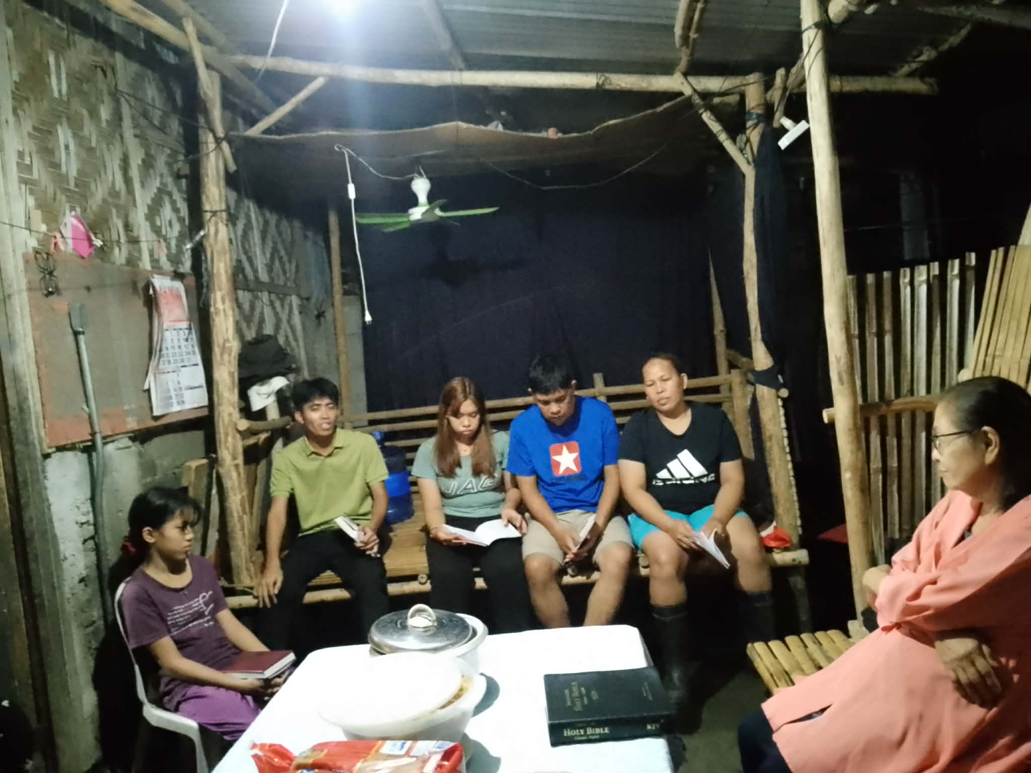 A family gathered around open Bibles during an evening home visit
