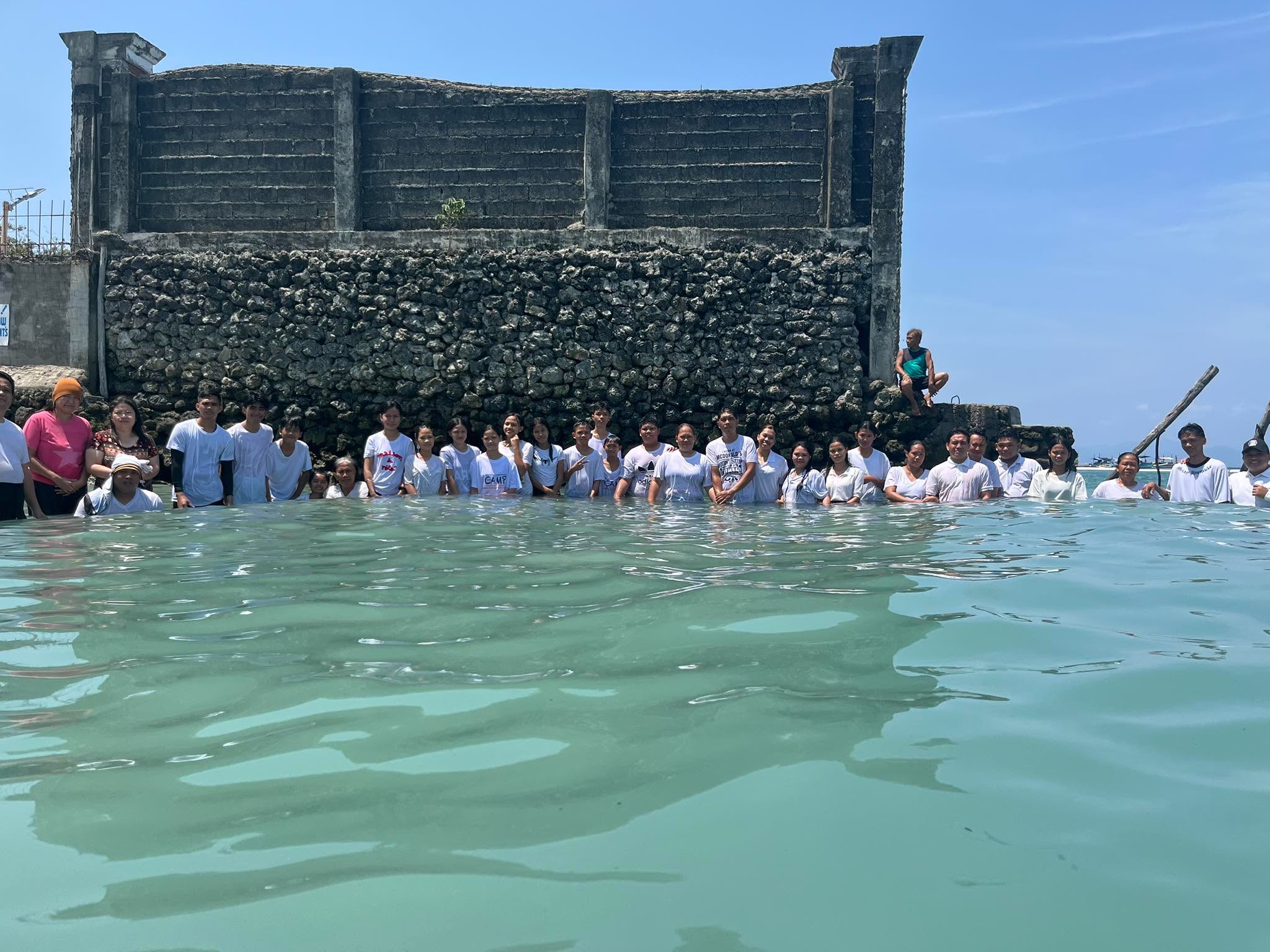 Church members standing together in the sea during a water baptism gathering